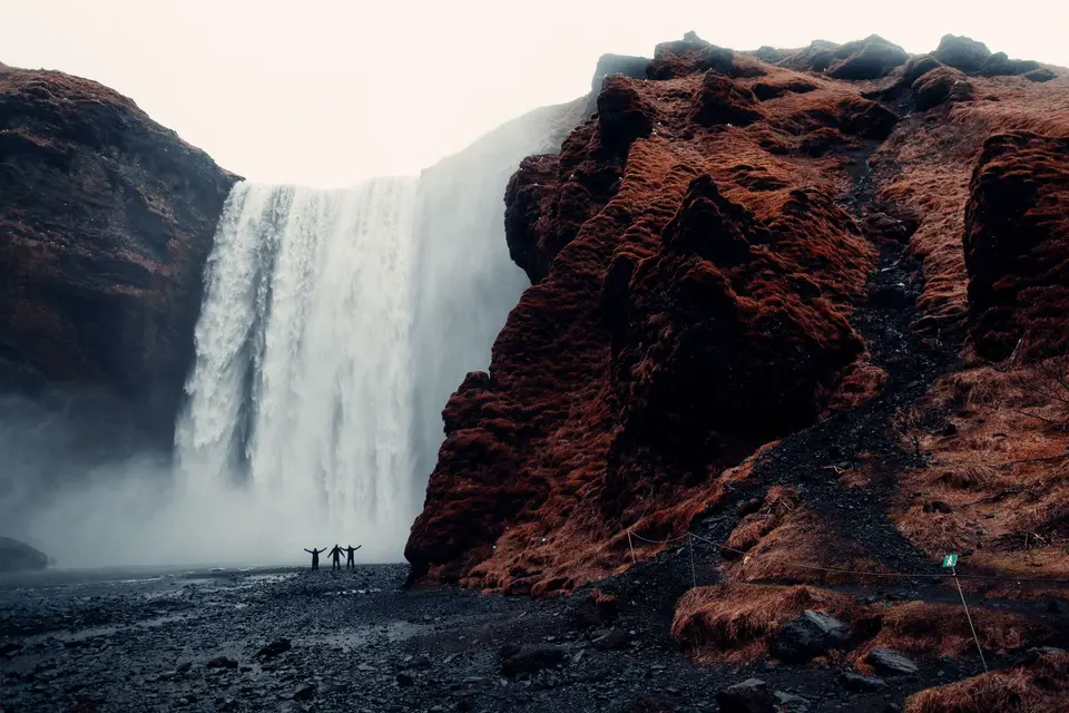 People standing in front of a tall waterfall