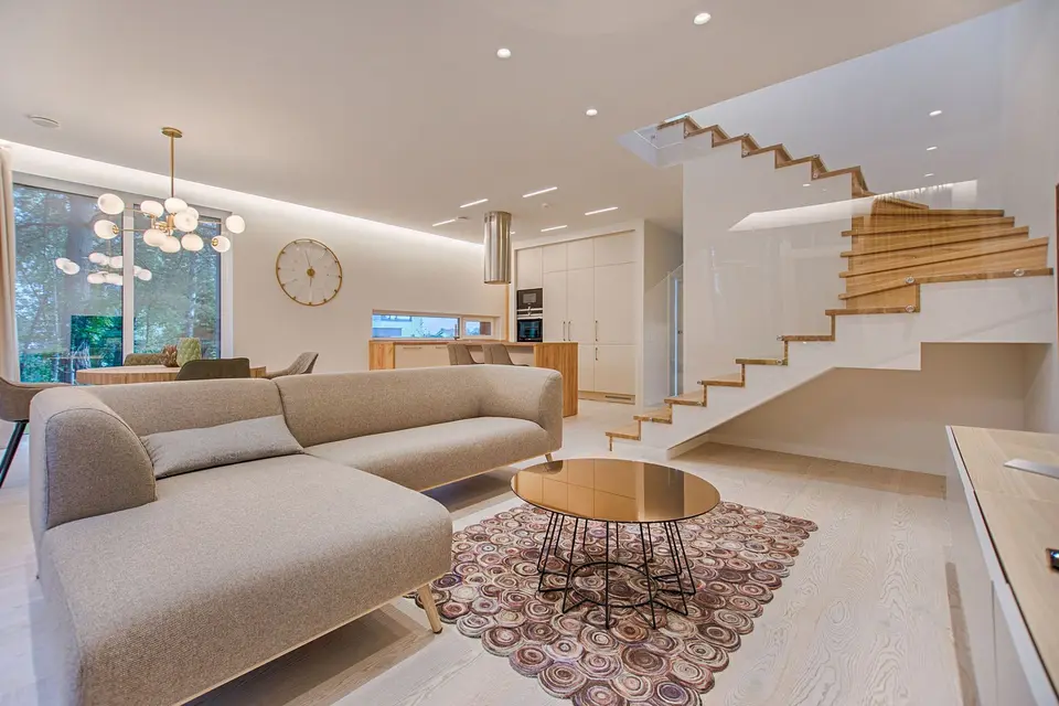 Phòng khách nắng với sofa be và cầu thang gỗ